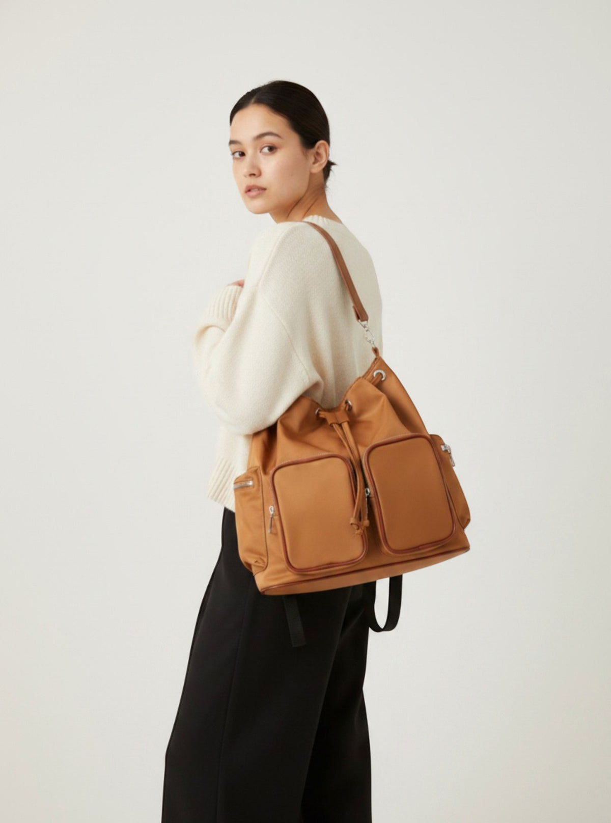 Model carrying Brettnie caramel convertible backpack