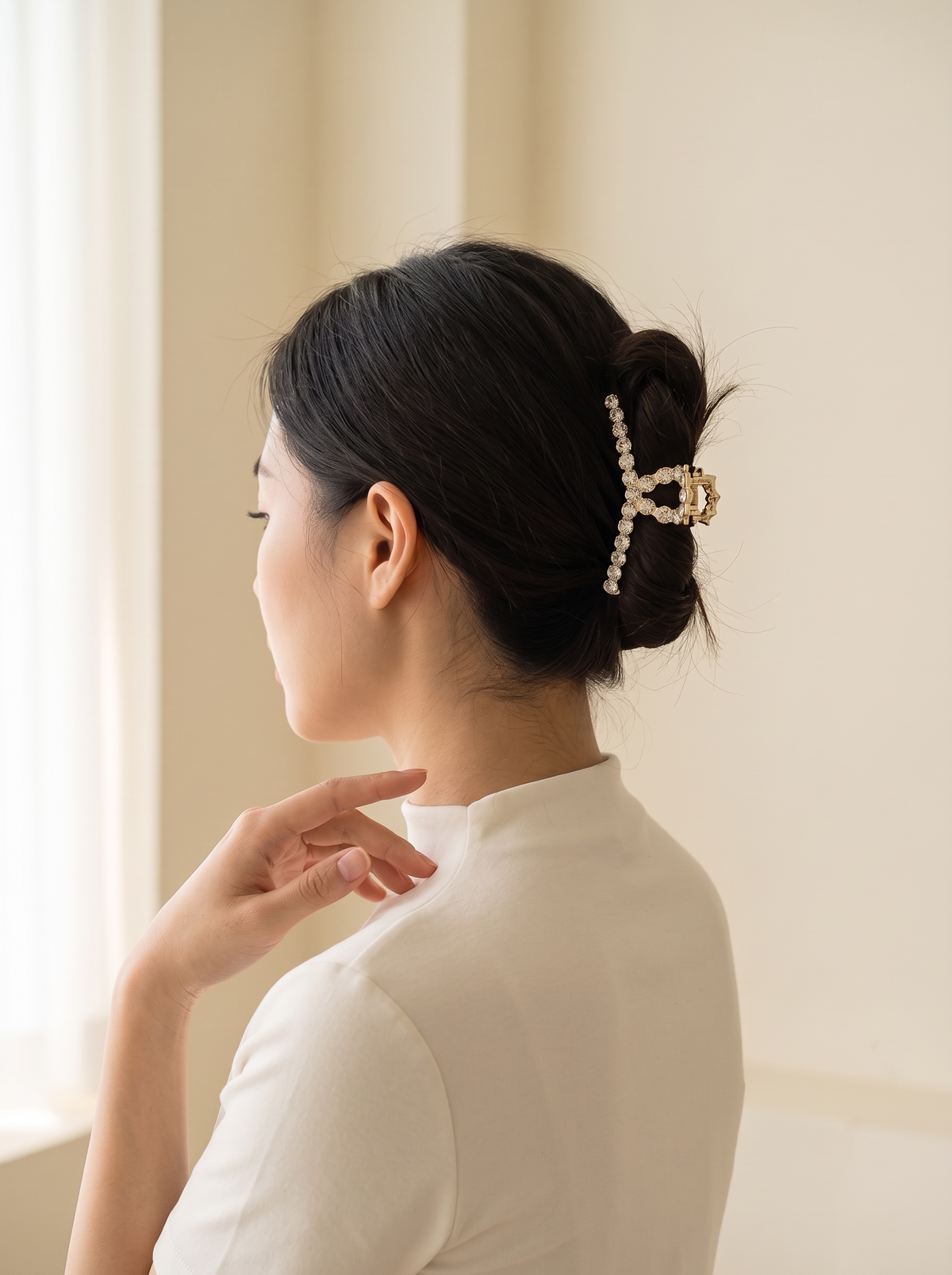 Model wearing Janina gold crystal claw clip in an updo