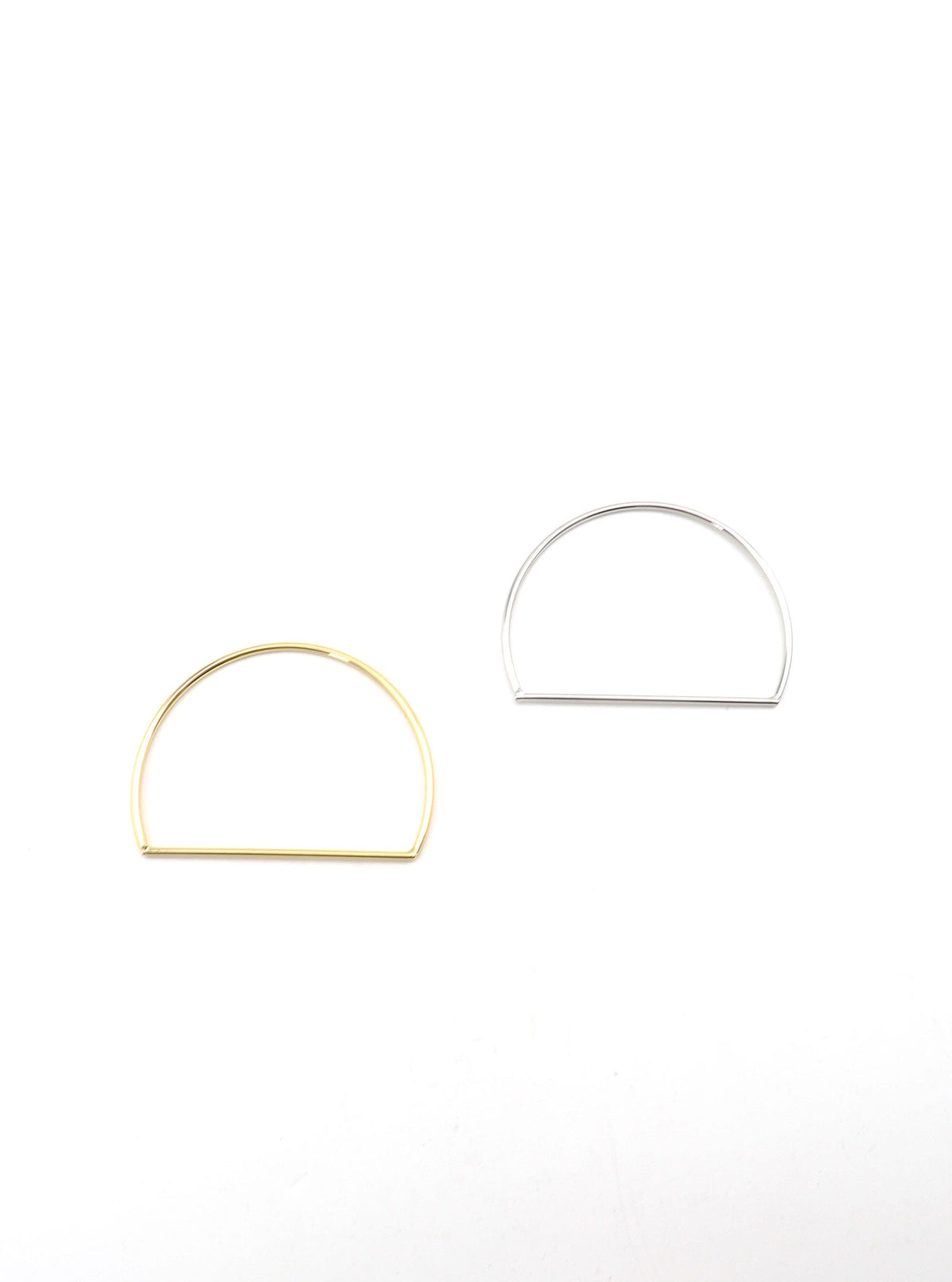 Gold and silver-tone Anito D-shaped bangles shown together on a white background.