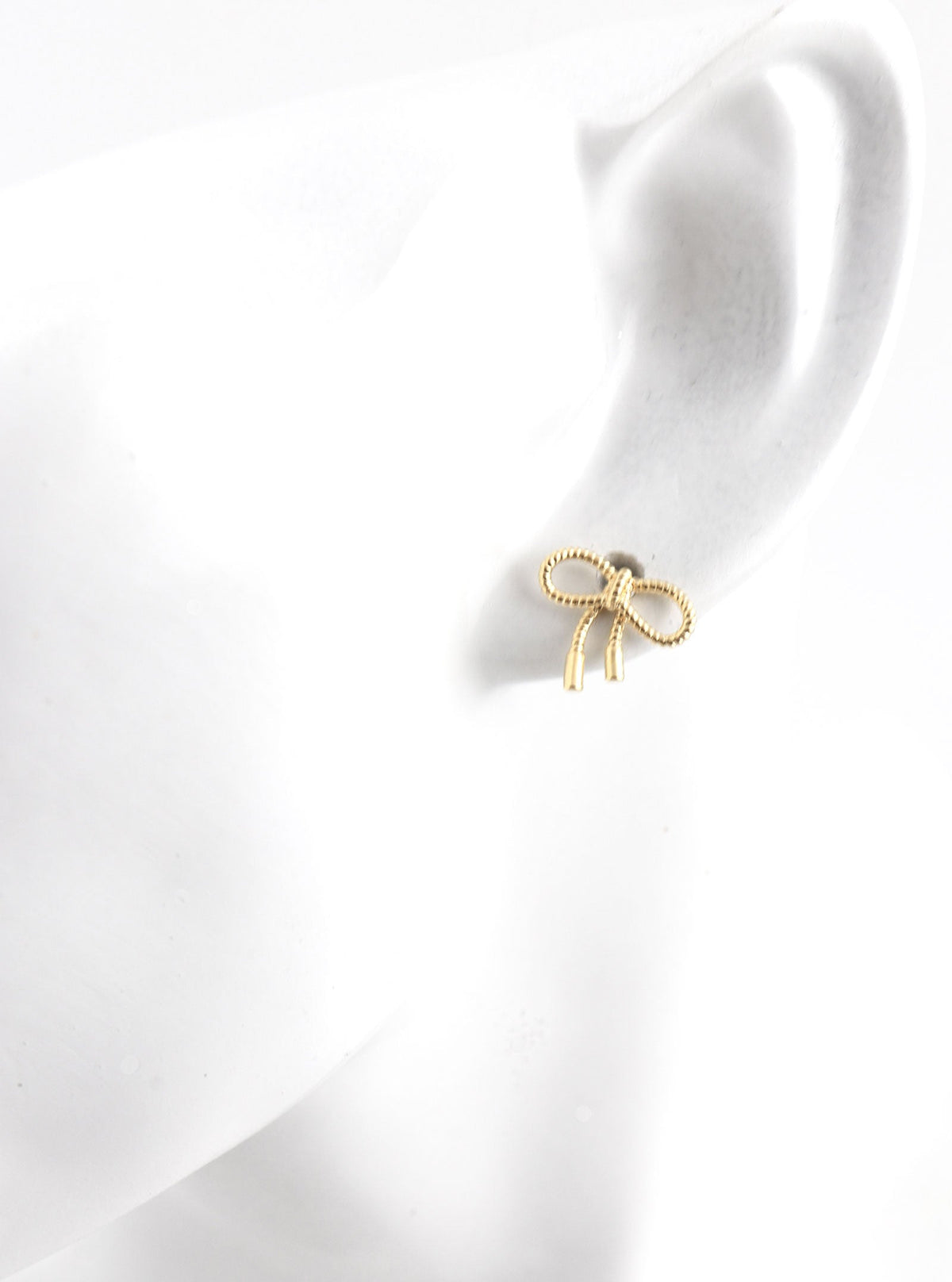 Tavora gold bow stud earring shown on an ear display