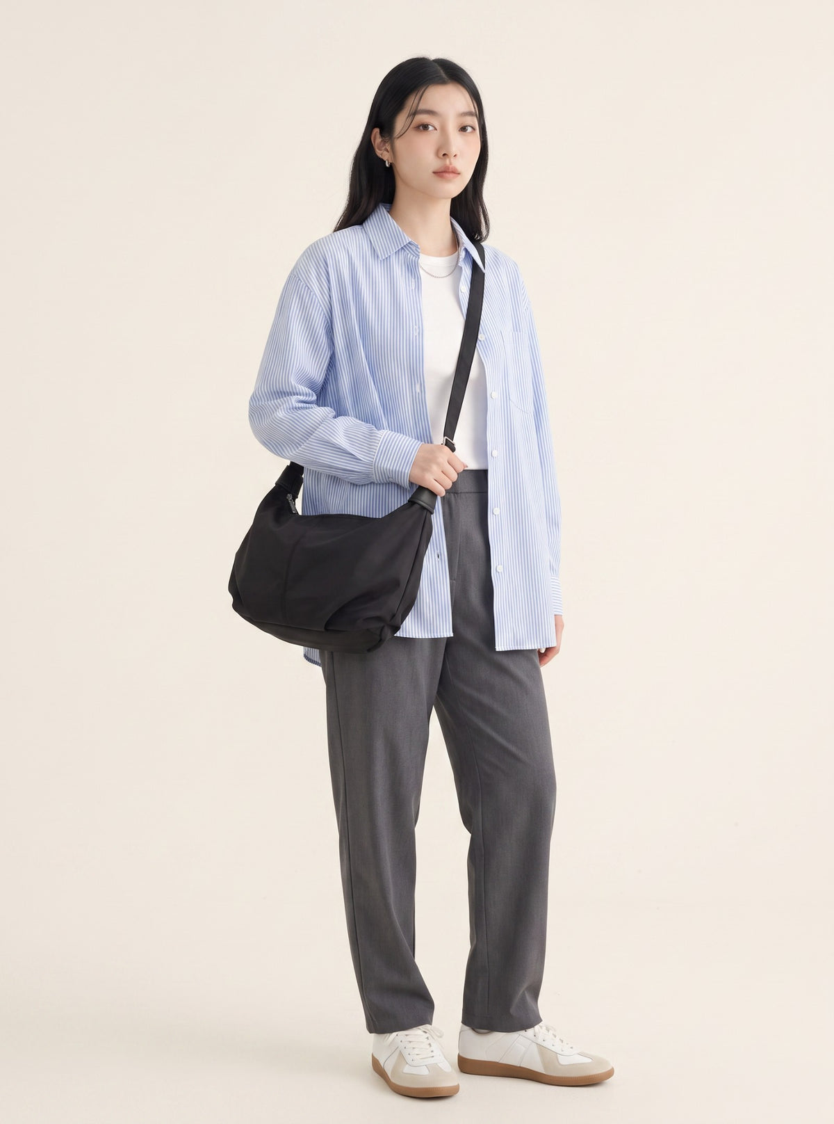 Model wearing Brickley black crossbody bag with a blue striped shirt