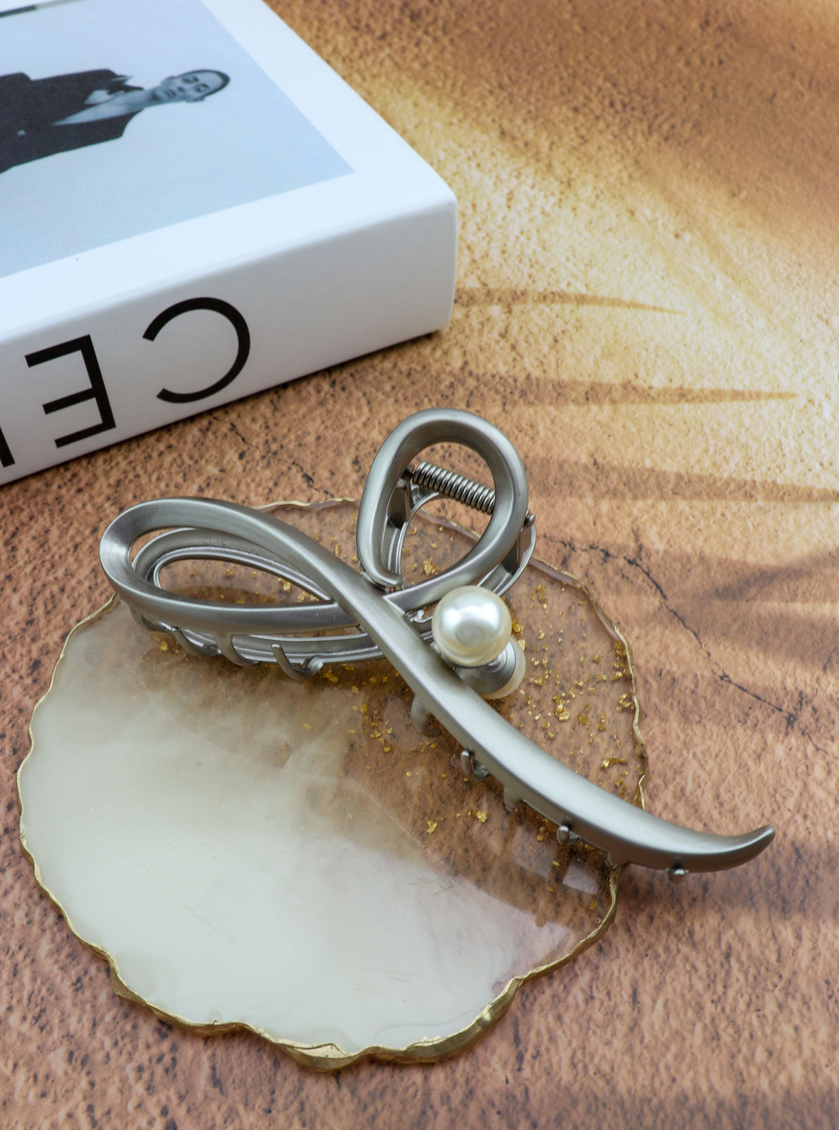 Jomena grey sculptural hair claw with pearl accent in a styled setting