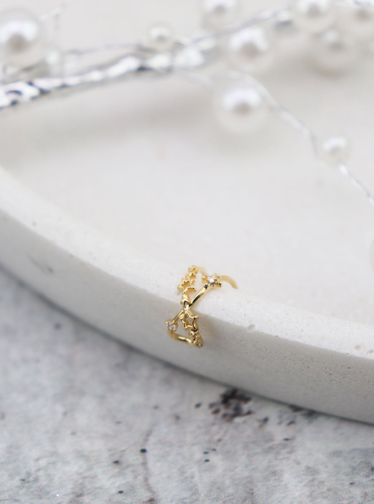 Tanvi gold star ear cuff styled on a neutral display