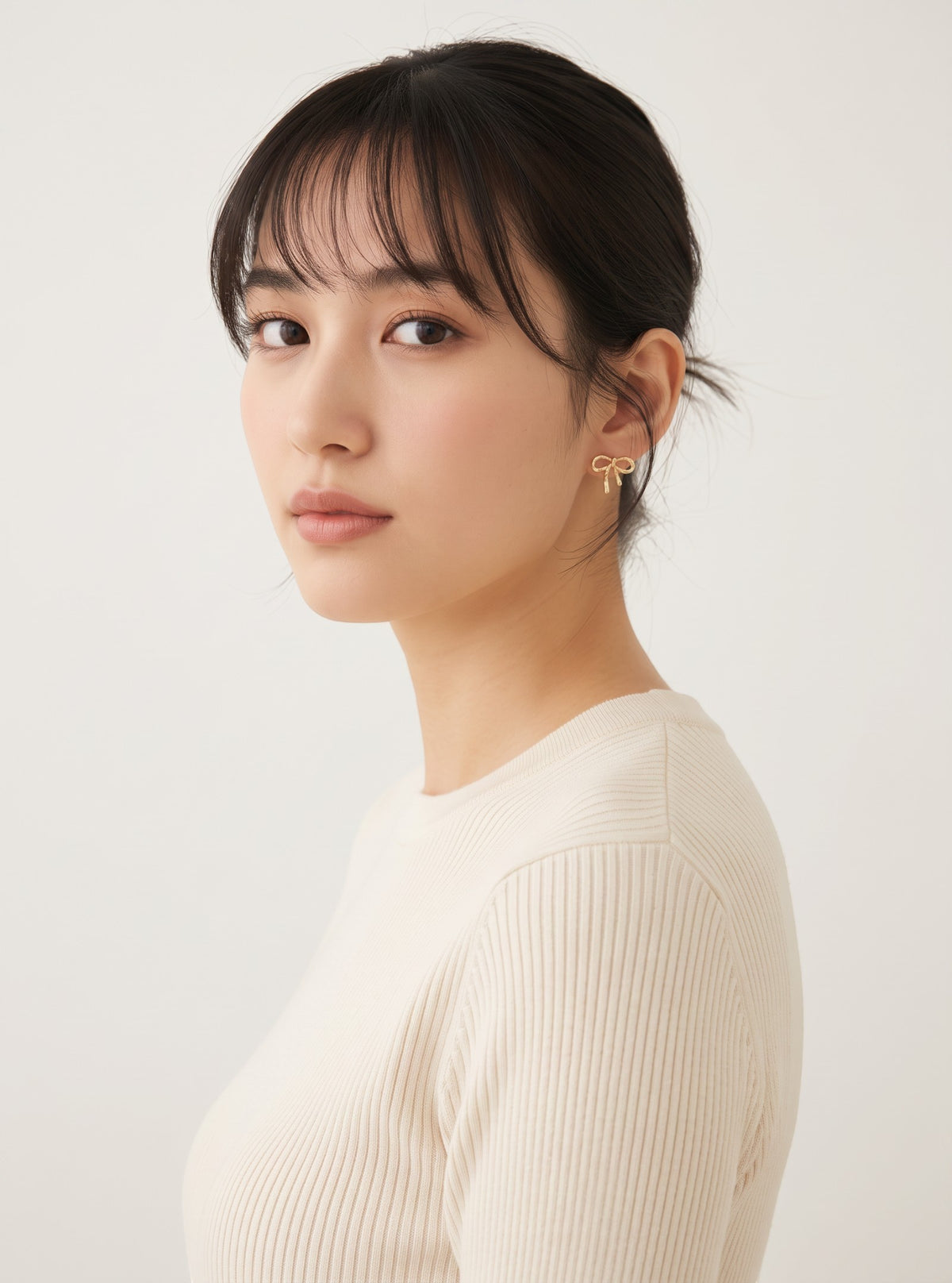Model wearing Tavora gold bow stud earrings